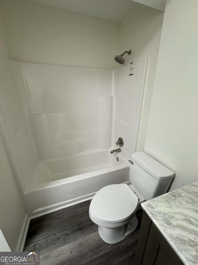 full bathroom with  shower combination, toilet, hardwood / wood-style floors, and vanity