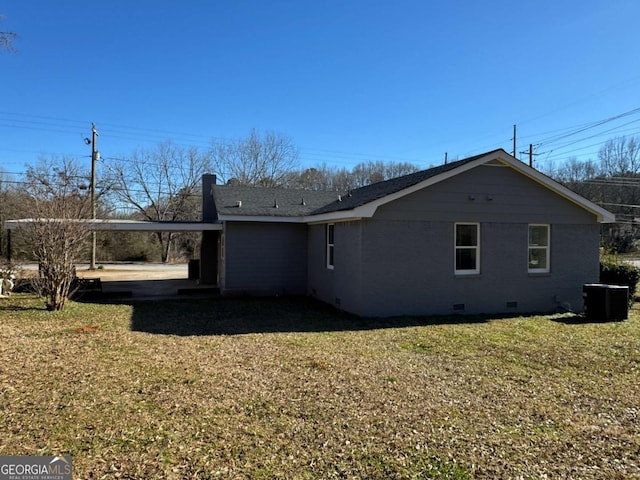 rear view of property with central air condition unit, a carport, and a lawn