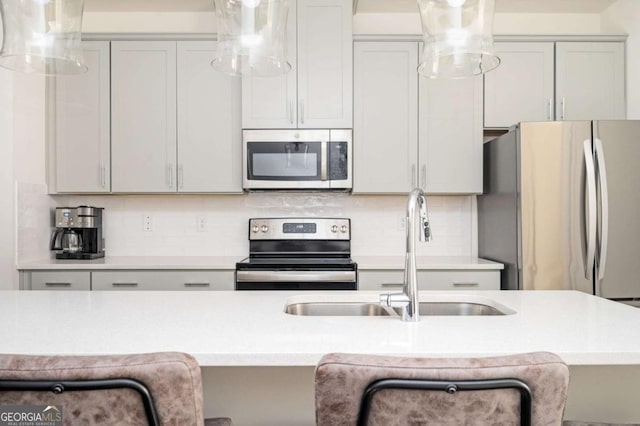 kitchen with sink, tasteful backsplash, a kitchen bar, and appliances with stainless steel finishes