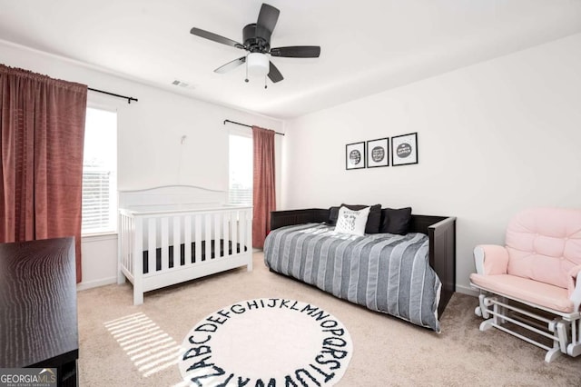 bedroom featuring ceiling fan, multiple windows, and light carpet