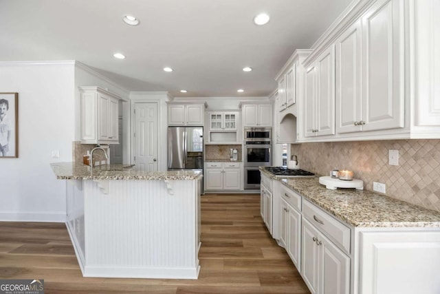 kitchen featuring white cabinets, stainless steel appliances, backsplash, kitchen peninsula, and hardwood / wood-style flooring