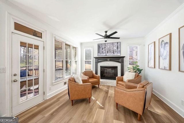 living area with crown molding, plenty of natural light, a fireplace, and light hardwood / wood-style floors