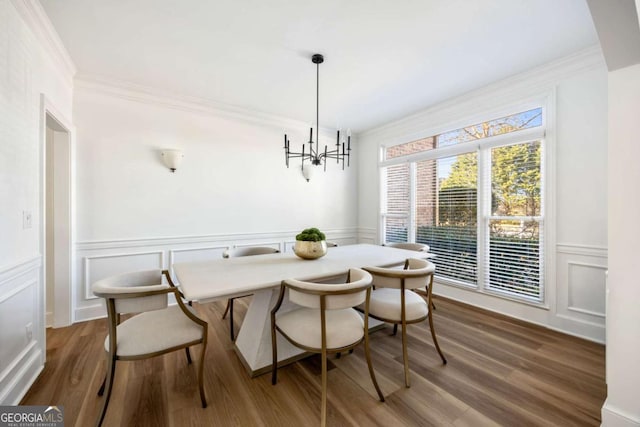 dining space with dark wood-type flooring, breakfast area, ornamental molding, and an inviting chandelier