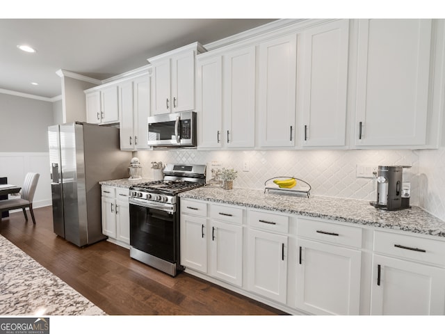 kitchen featuring crown molding, light stone countertops, white cabinetry, dark wood-type flooring, and stainless steel appliances