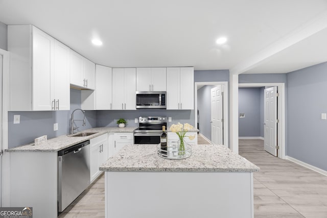 kitchen featuring white cabinetry, sink, stainless steel appliances, and a kitchen island