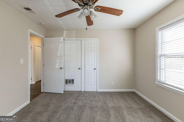 unfurnished bedroom with multiple windows, carpet flooring, a closet, and ceiling fan