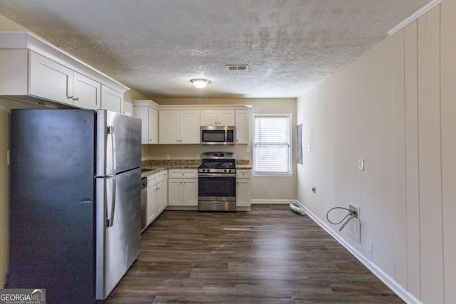 kitchen with white cabinetry, dark hardwood / wood-style floors, appliances with stainless steel finishes, and a textured ceiling