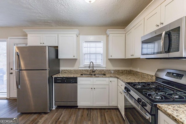 kitchen with sink, white cabinetry, light stone countertops, a textured ceiling, and stainless steel appliances