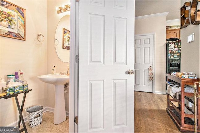 bathroom with crown molding, sink, and hardwood / wood-style floors