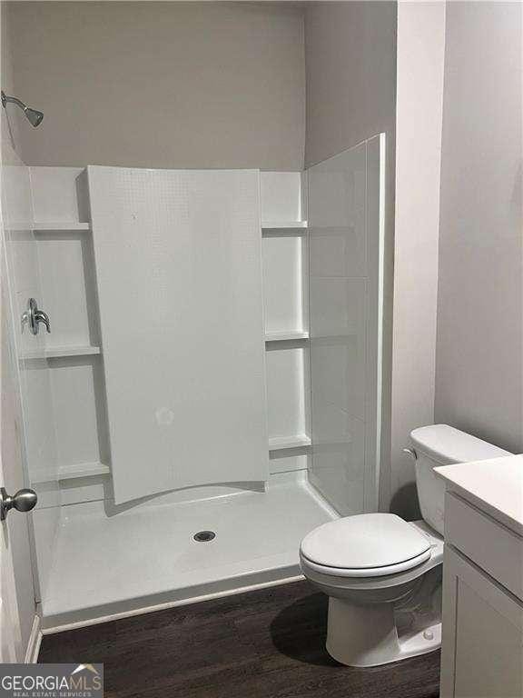 bathroom with vanity, toilet, a shower, and hardwood / wood-style flooring