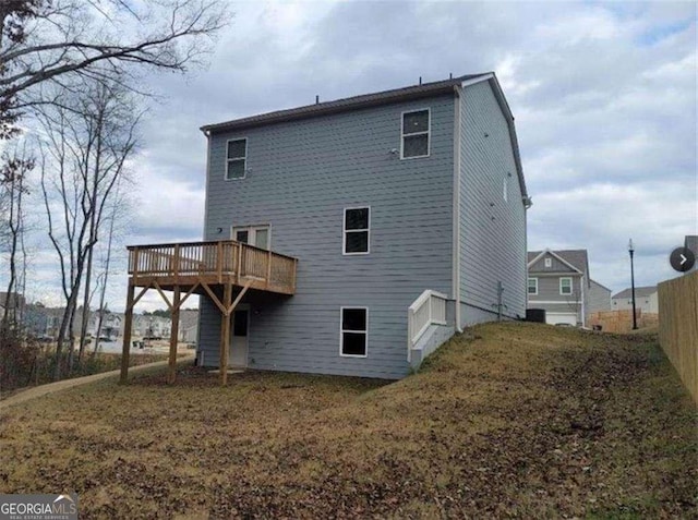 rear view of house featuring a deck and a lawn