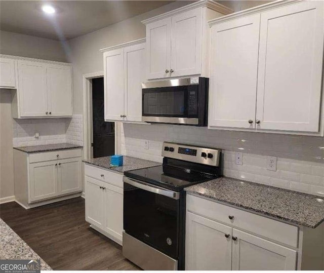 kitchen with light stone counters, white cabinets, dark hardwood / wood-style floors, and stainless steel appliances