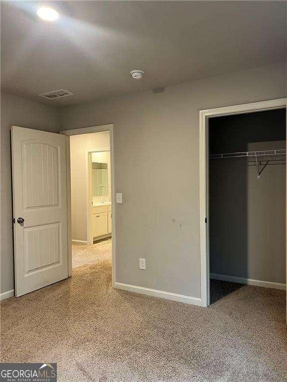 unfurnished bedroom with a closet and light colored carpet