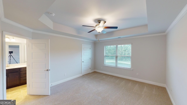 unfurnished bedroom with ceiling fan, ornamental molding, a tray ceiling, and light carpet