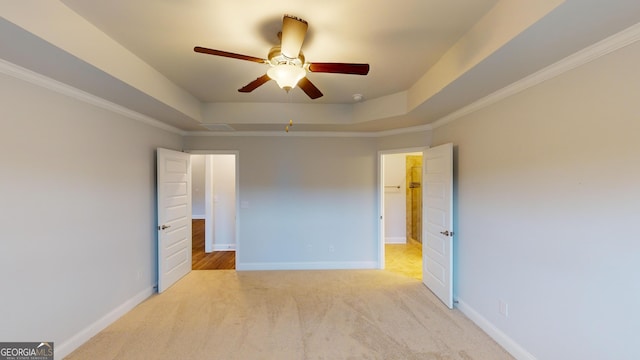 unfurnished room with ornamental molding, light colored carpet, a raised ceiling, and ceiling fan