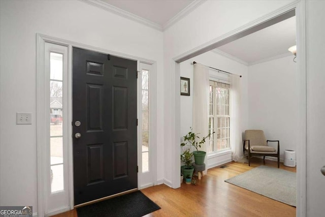 foyer with ornamental molding, a wealth of natural light, and light hardwood / wood-style flooring