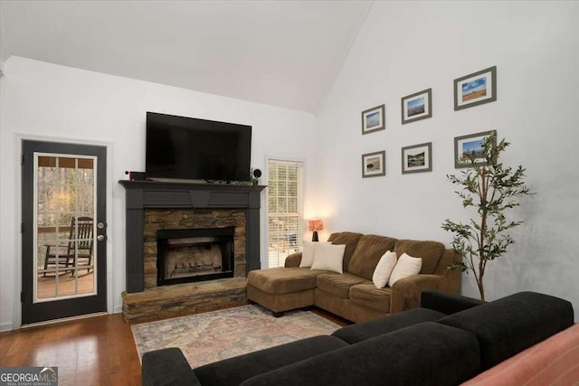 living room with hardwood / wood-style floors, high vaulted ceiling, and a stone fireplace