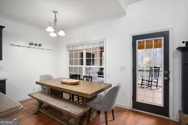 dining area with wood-type flooring, a chandelier, and ornamental molding