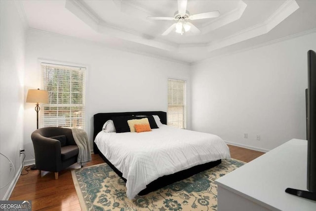 bedroom with ceiling fan, a raised ceiling, crown molding, and wood-type flooring