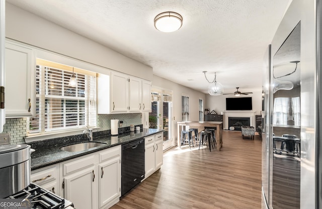 kitchen featuring sink, white cabinetry, tasteful backsplash, black dishwasher, and dark stone counters