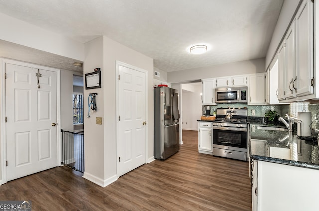 kitchen with sink, dark wood-type flooring, appliances with stainless steel finishes, white cabinetry, and tasteful backsplash