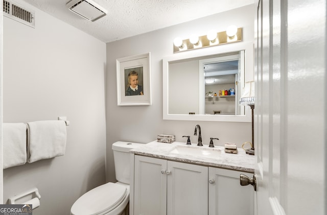 bathroom featuring vanity, toilet, and a textured ceiling