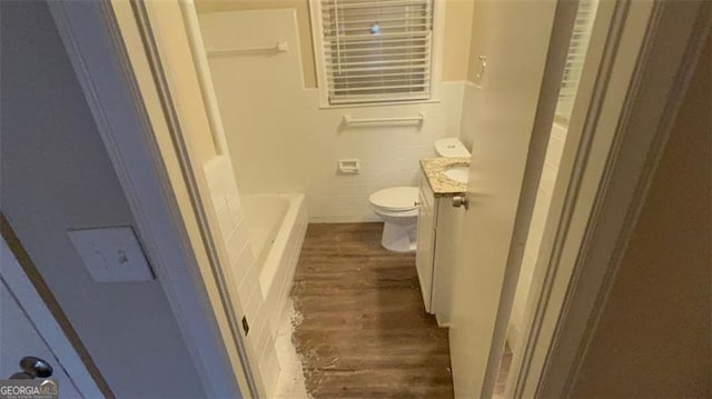 bathroom featuring hardwood / wood-style flooring, toilet, vanity, and a tub