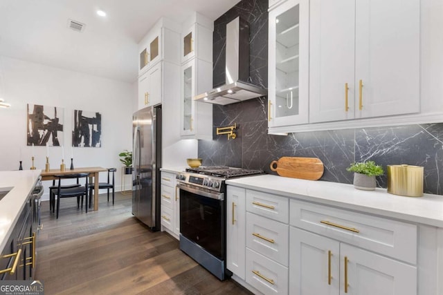 kitchen with white cabinets, appliances with stainless steel finishes, wall chimney exhaust hood, dark wood-type flooring, and backsplash