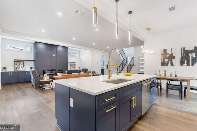 kitchen with dishwasher, hanging light fixtures, light wood-type flooring, sink, and a center island with sink