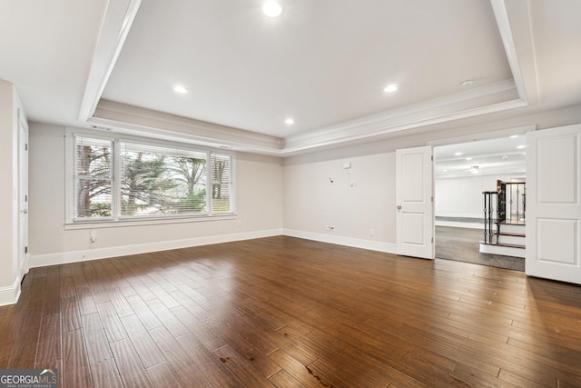 unfurnished living room featuring dark wood-type flooring and a tray ceiling