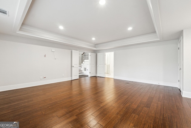 unfurnished living room featuring a raised ceiling and dark hardwood / wood-style flooring