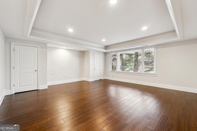 empty room with dark hardwood / wood-style floors and a raised ceiling