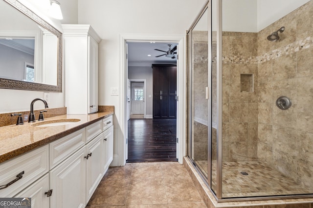 bathroom with ceiling fan, ornamental molding, a shower with door, and vanity