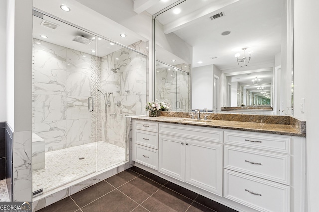 bathroom featuring an inviting chandelier, vanity, a shower with shower door, and tile patterned flooring