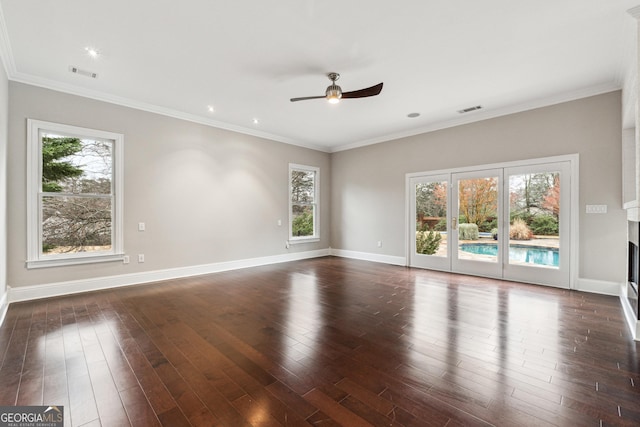 empty room featuring crown molding, ceiling fan, a healthy amount of sunlight, and dark wood-type flooring