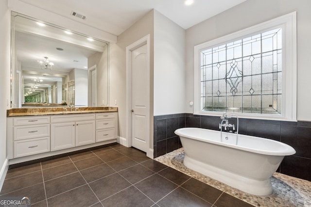 bathroom featuring a bathing tub, tile walls, tile patterned floors, and vanity