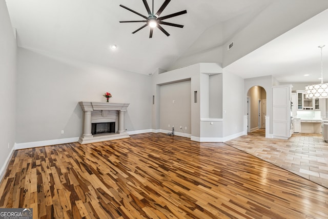 unfurnished living room featuring ceiling fan, high vaulted ceiling, and light wood-type flooring