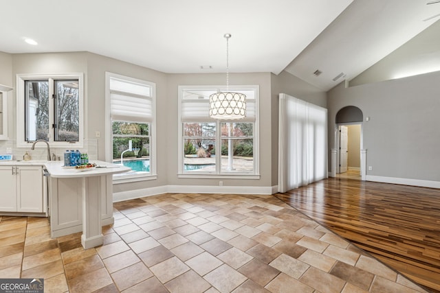 unfurnished dining area featuring sink, light tile patterned floors, and vaulted ceiling