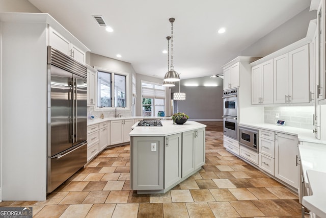 kitchen with built in appliances, decorative backsplash, a center island, and white cabinets