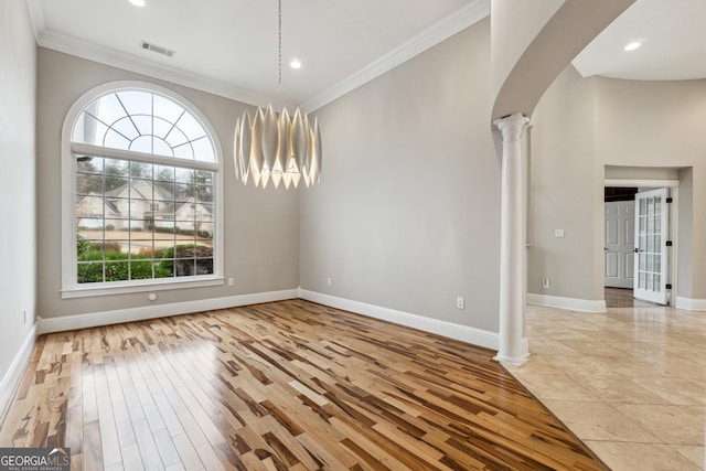 unfurnished dining area featuring ornamental molding, decorative columns, and light hardwood / wood-style flooring