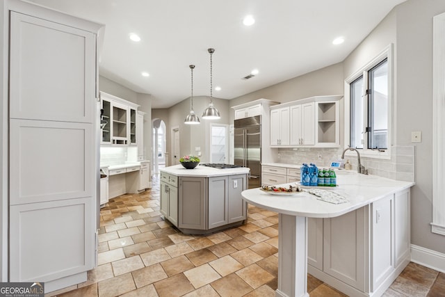 kitchen featuring tasteful backsplash, plenty of natural light, a kitchen island, pendant lighting, and stainless steel appliances