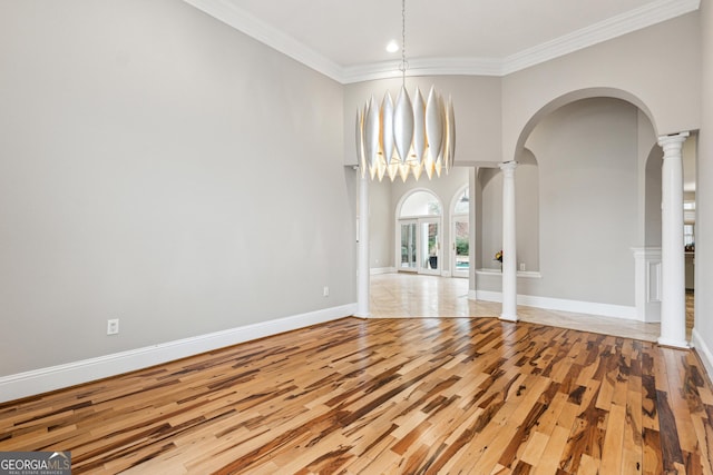 unfurnished dining area featuring crown molding, decorative columns, and light hardwood / wood-style floors