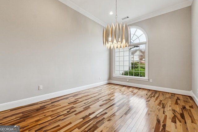 unfurnished dining area featuring ornamental molding, hardwood / wood-style floors, and an inviting chandelier