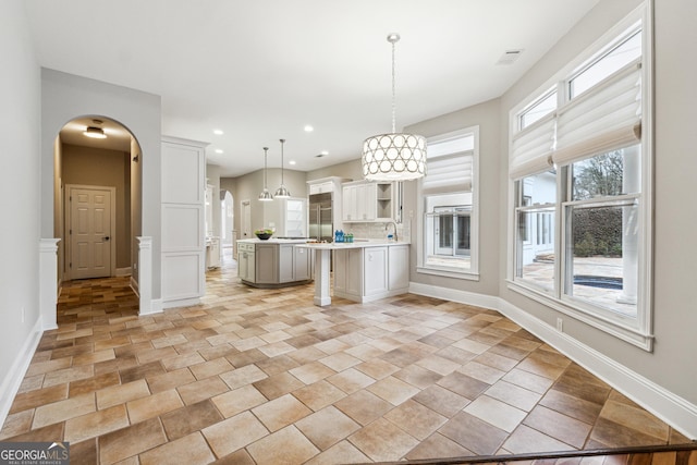 kitchen featuring backsplash, a kitchen breakfast bar, white cabinets, a kitchen island, and decorative light fixtures