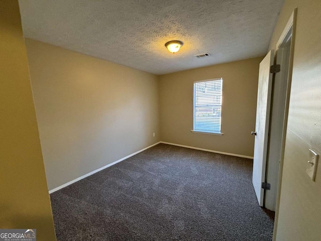 empty room featuring dark carpet and a textured ceiling