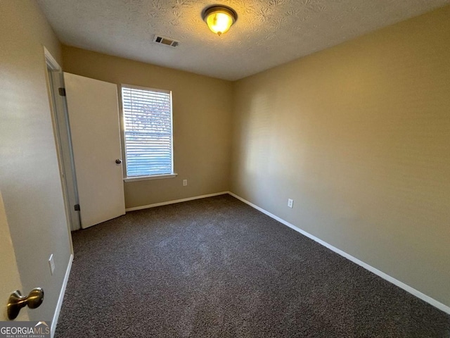 empty room with a textured ceiling and carpet floors