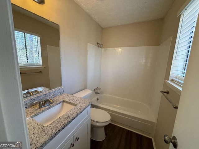 full bathroom featuring a textured ceiling, shower / bathing tub combination, wood-type flooring, vanity, and toilet