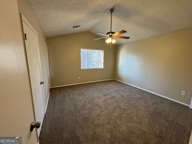 interior space with vaulted ceiling, dark carpet, ceiling fan, and a textured ceiling