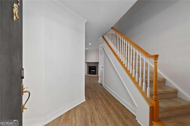 stairs with wood-type flooring and crown molding