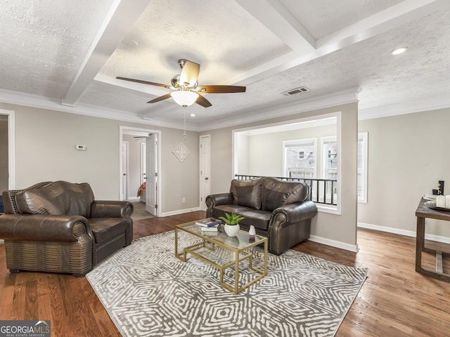 living room with wood-type flooring, a textured ceiling, ornamental molding, and beam ceiling